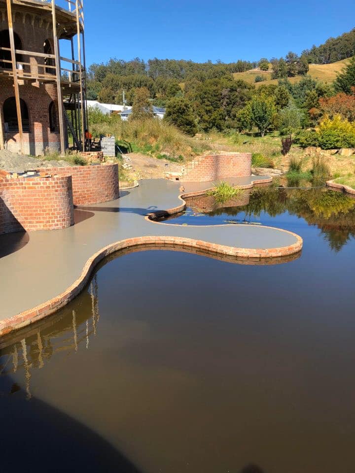 Custom curved concrete with brick edging beside a pond on a rural Tasmanian property